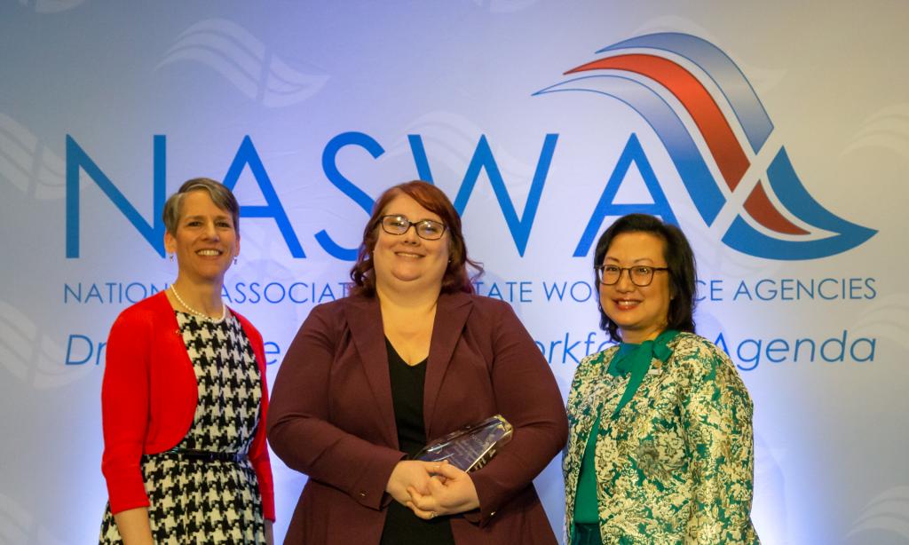 Accepting the Merrill Baumgardner Award, Suzi Levine, Commissioner, and Lissa Kissler, PFML Technology Manager, Washington State Employment Security Department, pose with Anna Hui, NASWA Board President.